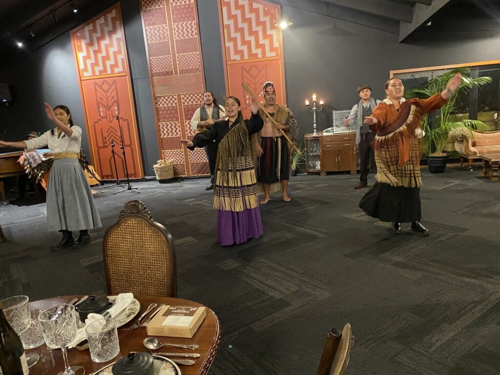 Traditionelle Māori-Tanzvorführung in einem dekorierten Raum mit gedecktem Tisch.